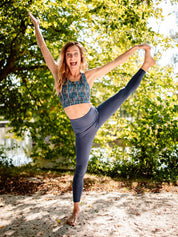 Frau praktiziert Yoga im Freien und trägt das nachhaltige Fitness-Bustier 'Gélinotte' mit Blättermotiv mit gekreuzten Trägern für optimalen Halt.