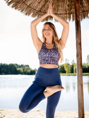 Frau praktiziert Yoga im Freien und trägt das Fitness-Bustier 'GÉLINOTTE' MIT ZEBRAMUSTER – atmungsaktiv, feuchtigkeitsregulierend und mit gekreuzten Trägern für optimalen Halt.