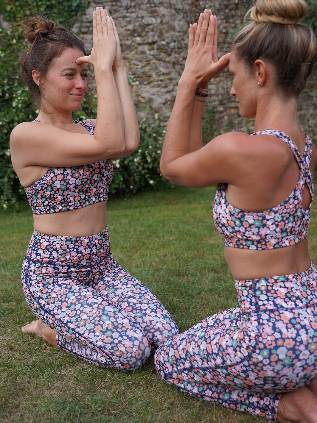 Zwei Frauen im Freien, die das Fitness-Leggings ‘Colibri’ mit Blumenmotiv tragen und Yoga machen