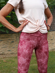 Frau im Yoga-Outfit in der Natur, trägt Bordeaux Colibri-Leggings mit Blumenmotiv, elegant und funktionell