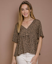 Frau trägt Blusentop mit Leo-Print aus EcoVero-Viskose, nachhaltige Damenmode aus Frankreich, luftiger Schnitt, elegante Sommerbluse.