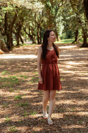 Sommerkleid "Mathilde" – getragen im Park.-Sommerkleid aus 100 % Leinen in Terrakotta – feminine Silhouette und französischer Charme unter schattigen Bäumen.
