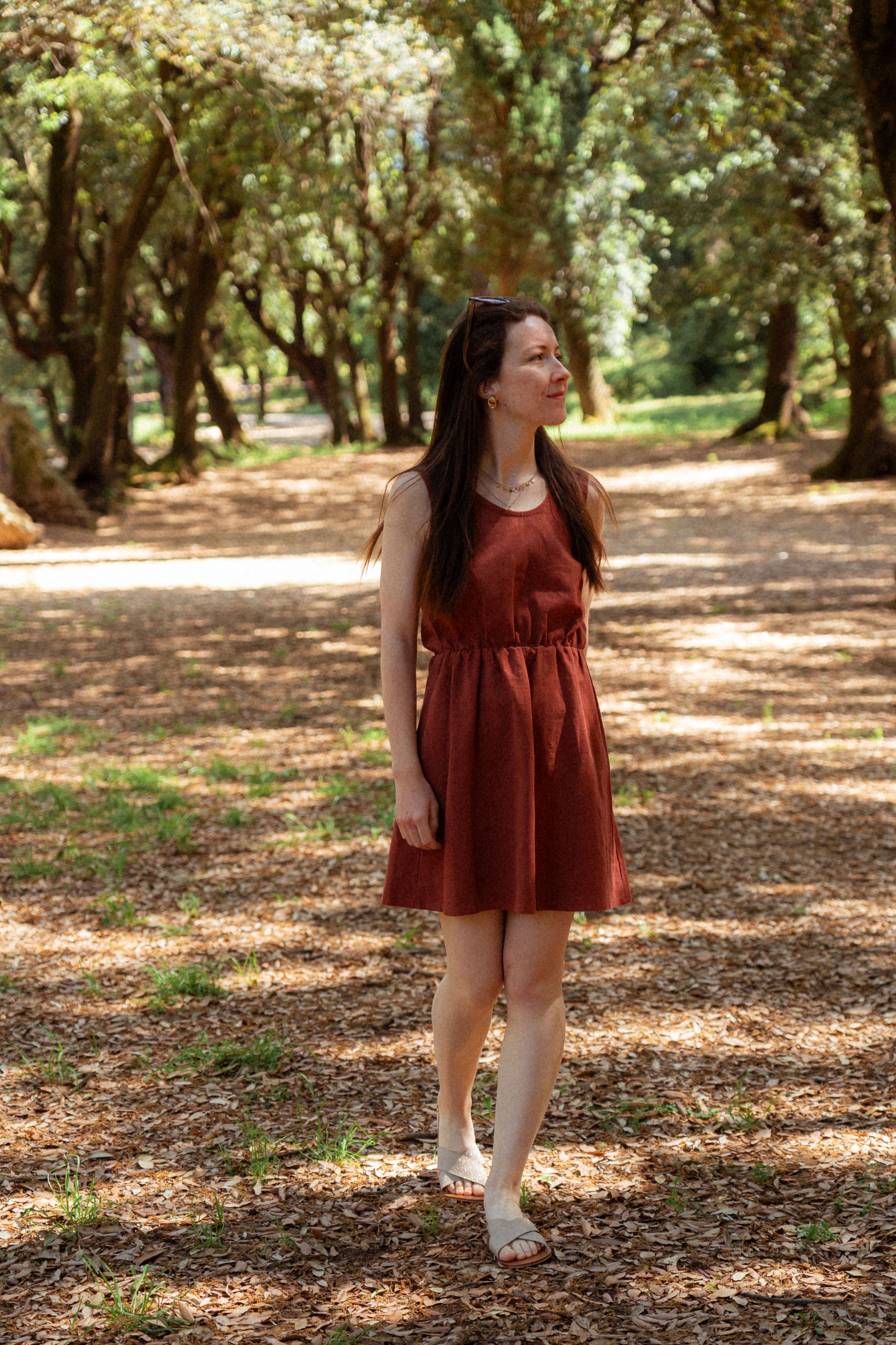 Sommerkleid "Mathilde" – getragen im Park.-Sommerkleid aus 100 % Leinen in Terrakotta – feminine Silhouette und französischer Charme unter schattigen Bäumen.