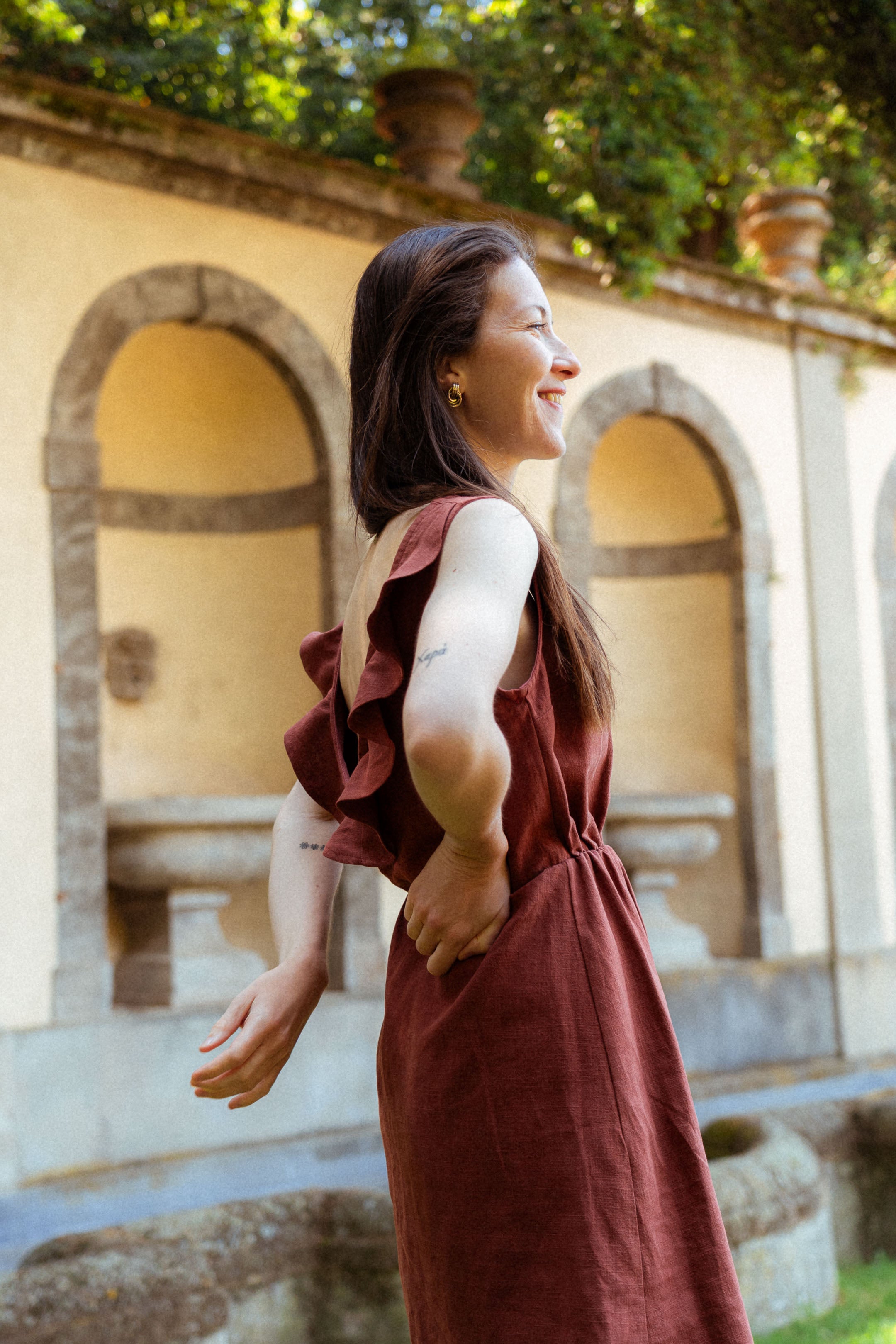 Kleid "Mathilde" – Seitenansicht beim Gehen im Park. Elegantes Leinenkleid für Damen mit elastischer Taille und Volant-Detail – perfekte nachhaltige Mode für warme Sommertage.