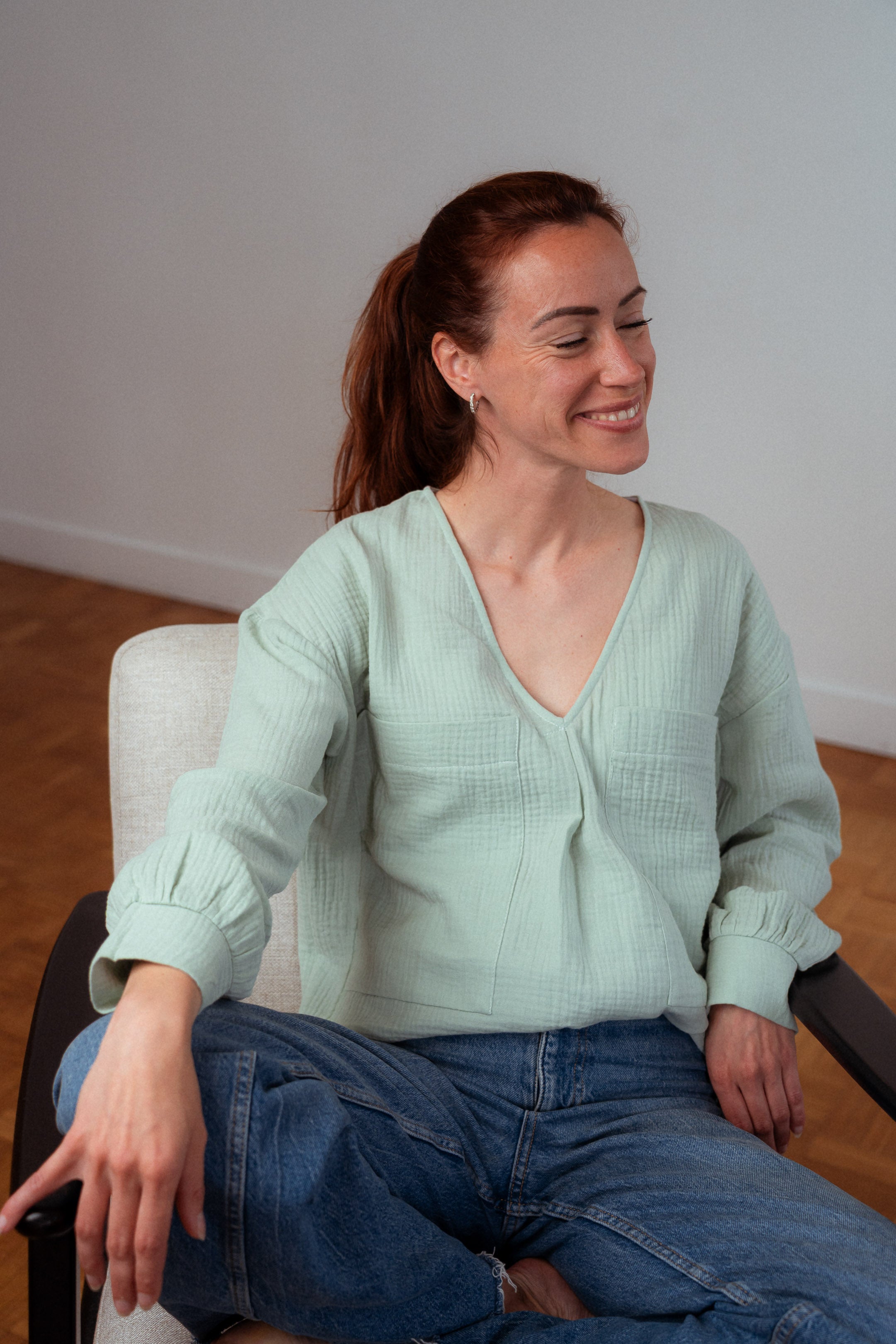 Stillbluse Tiphaine in Aqua-Grün – Mutter hält ihr Baby im Arm, trägt eine bequeme Stillbluse aus Bio-Baumwolle.