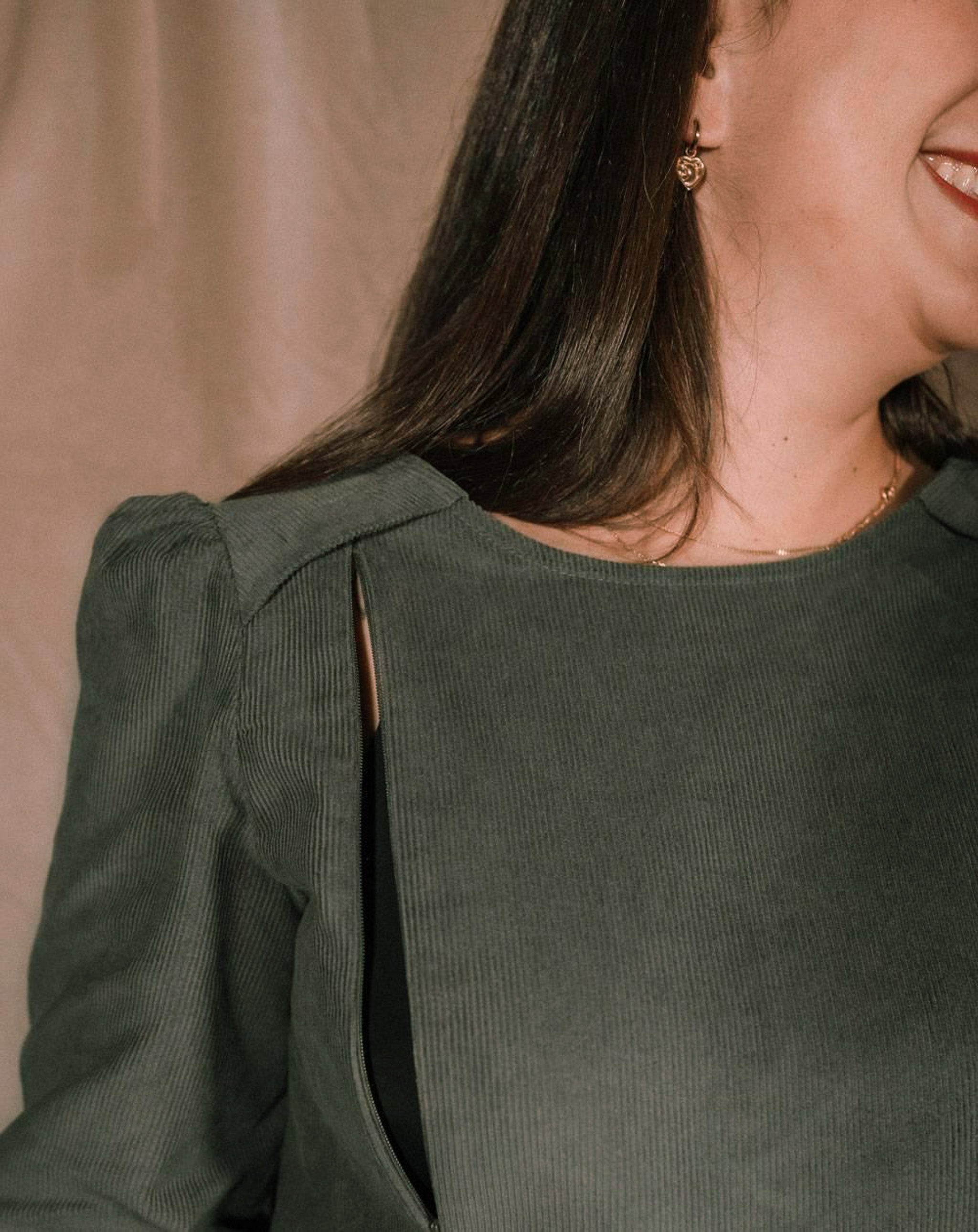 Nahaufnahme des Stillkleids Maria aus Cord in Grau-Grün, die den eleganten Stoff und die diskrete Stillöffnung zeigt.