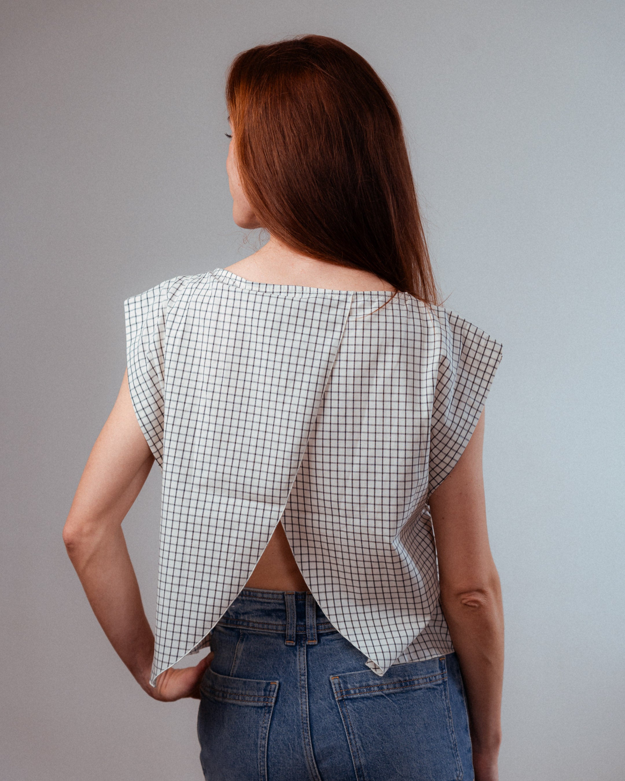 Frau trägt das Stilltop mit Karomuster Léna im Rückenansicht und zeigt den eleganten, offenen Rücken im Cache-Cœur-Design.