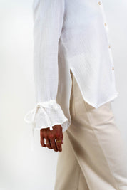 Nahaufnahme des Knotens am Ärmel der weißen Bluse Noosa. Ein raffiniertes Detail, das die Vielseitigkeit und den zeitlosen Stil der Bluse unterstreicht.