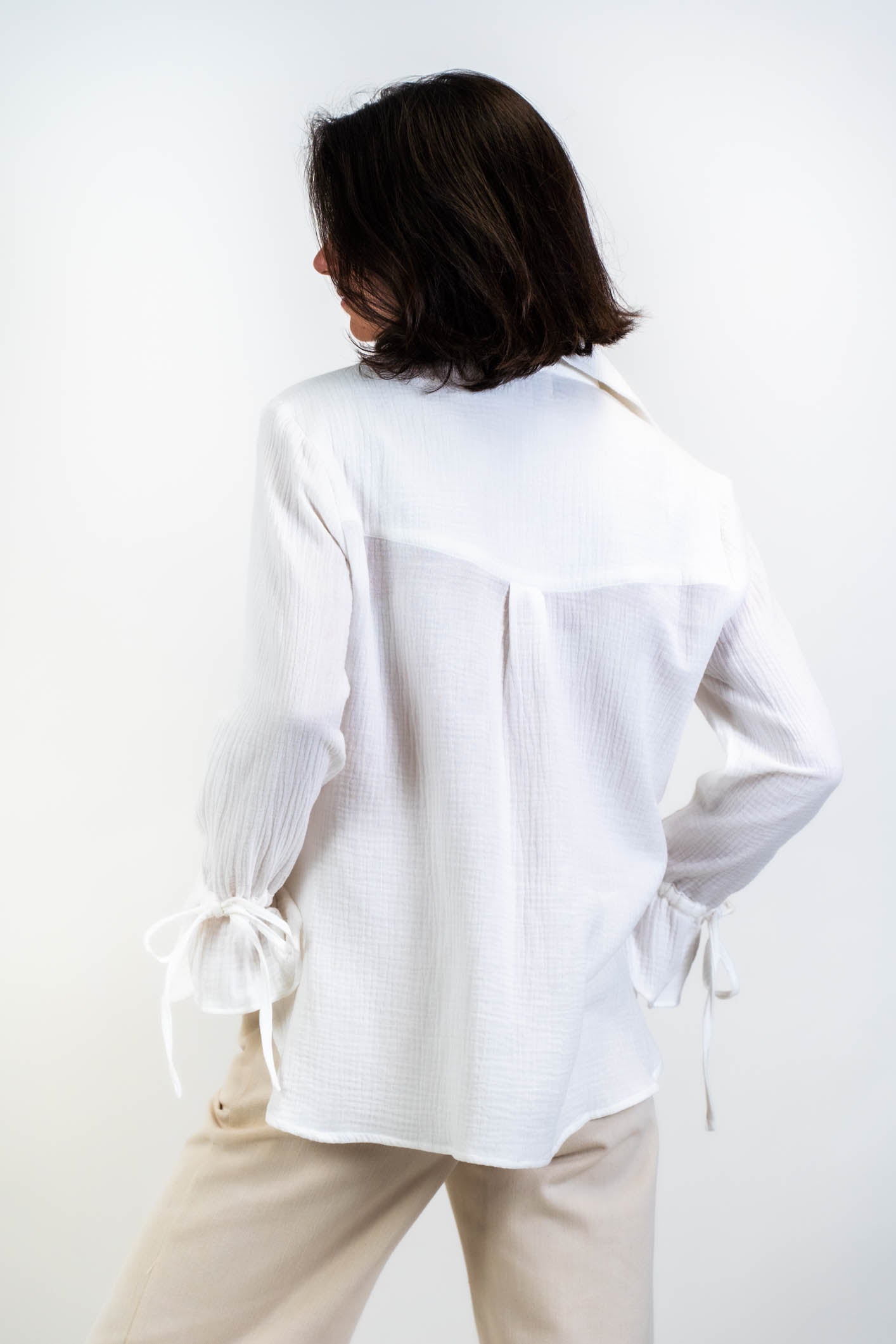 Die weiße Bluse Noosa aus doppellagiger Baumwollgaze, präsentiert im Studio mit Blick von hinten. Zeigt die schlichte Rückenansicht und die raffinierten Details.