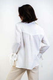 Die weiße Bluse Noosa aus doppellagiger Baumwollgaze, präsentiert im Studio mit Blick von hinten. Zeigt die schlichte Rückenansicht und die raffinierten Details.
