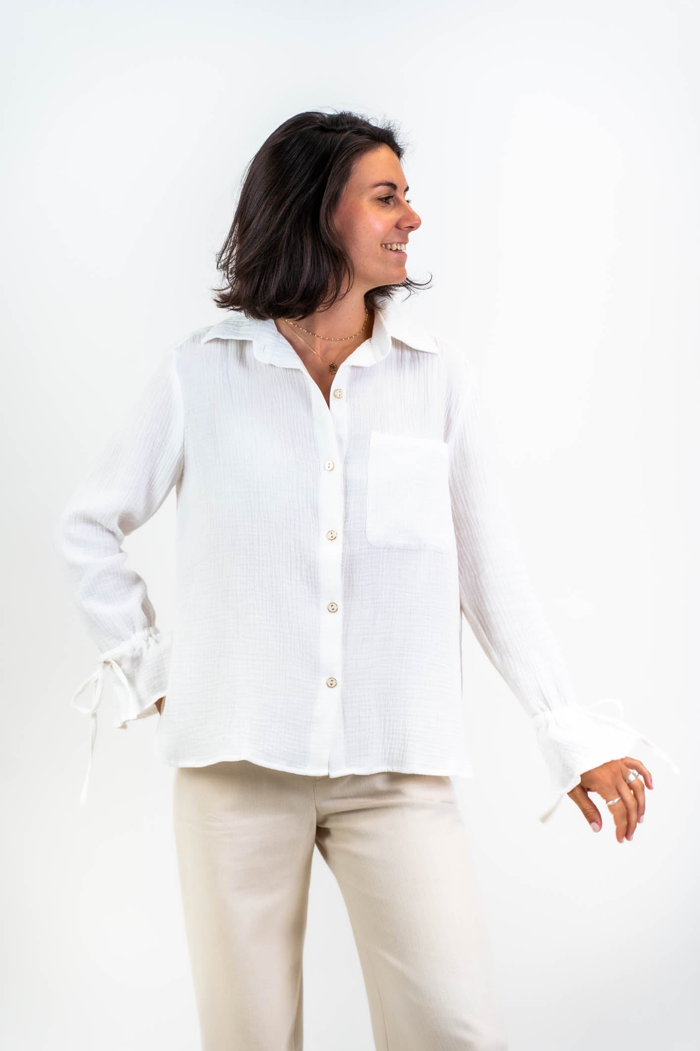 Die weiße Bluse Noosa aus doppellagiger Baumwollgaze, präsentiert im Studio mit Blick von vorne. Minimalistisches Design mit zeitloser Eleganz.