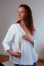 Nahaufnahme der weißen Stillbluse Camille. Die versteckten Reißverschlüsse an den Seiten ermöglichen ein komfortables und diskretes Stillen, ohne die Eleganz der Bluse zu beeinträchtigen.