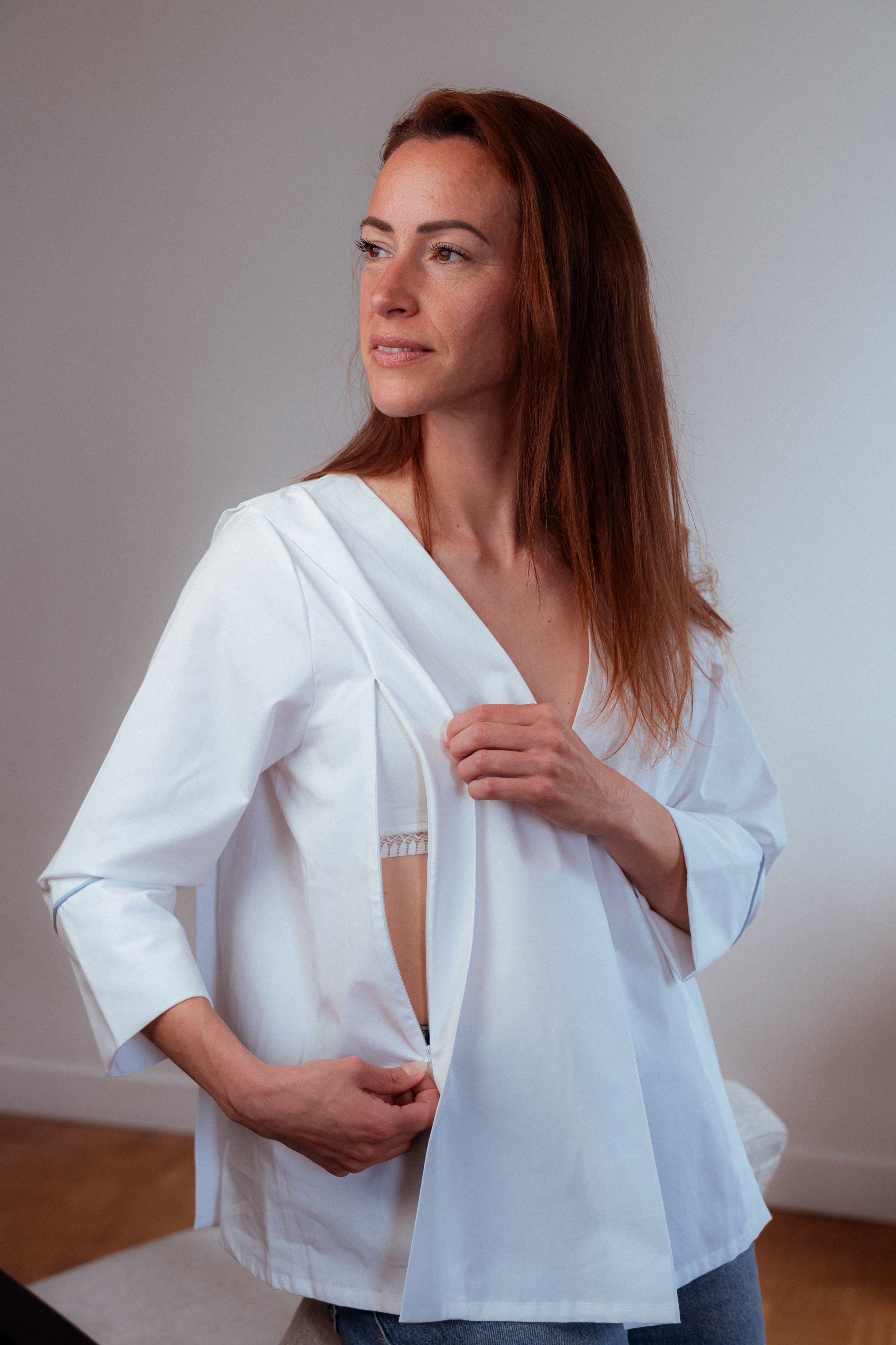Nahaufnahme der weißen Stillbluse Camille. Die versteckten Reißverschlüsse an den Seiten ermöglichen ein komfortables und diskretes Stillen, ohne die Eleganz der Bluse zu beeinträchtigen.
