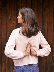 Frau trägt das 'Héron' Sweatshirt in Rosa im Freien – elegantes und bequemes Design für sportliche Aktivitäten und Entspannung.