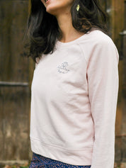 Frau entspannt sich im Freien und trägt das 'Héron' Sweatshirt in Rosa – ideal für Sport und Erholung.