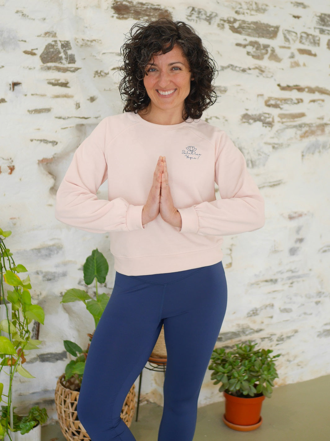 Frau praktiziert Yoga im Innenbereich und trägt das 'Héron' Sweatshirt in Rosa, ideal für Training und Entspannung.