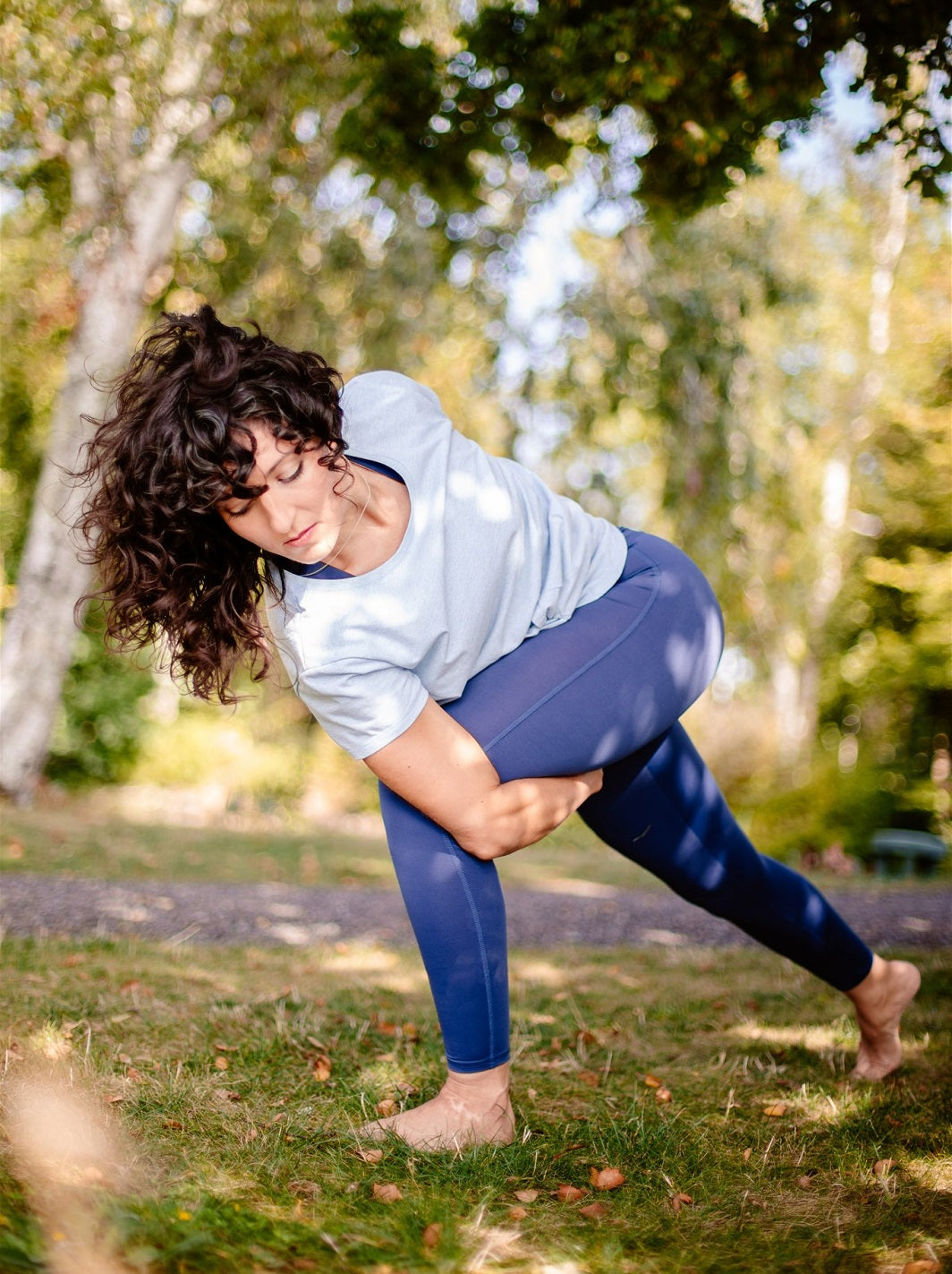 Yoga-Praxis im Freien – Frau trägt das ergonomische T-Shirt „Toucan“ in Himmelblau mit Knotendetail