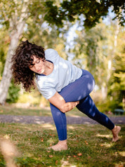 Yoga-Praxis im Freien – Frau trägt das ergonomische T-Shirt „Toucan“ in Himmelblau mit Knotendetail