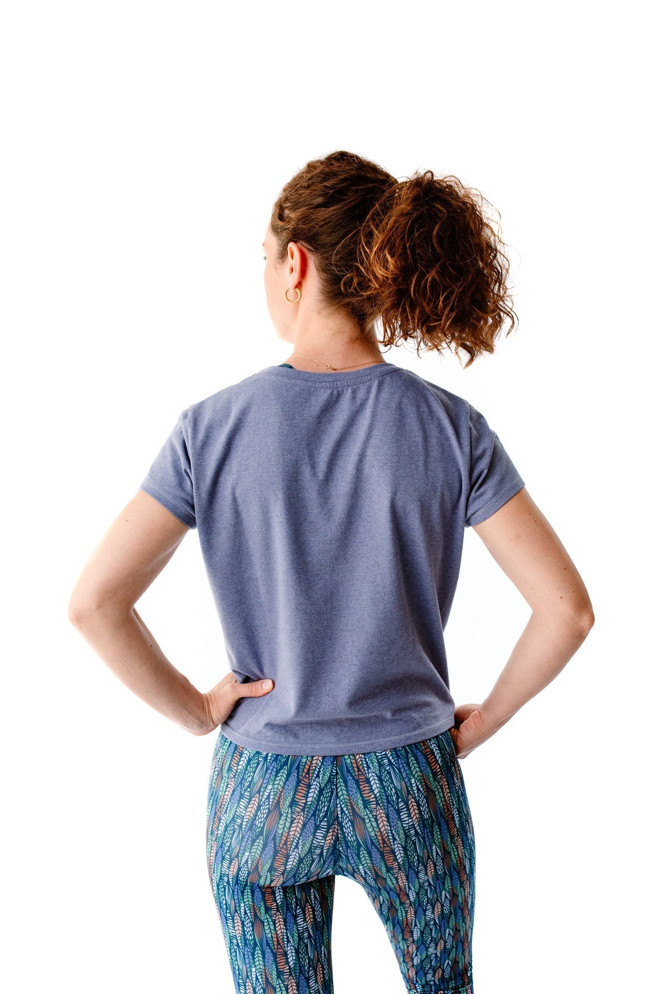Frau trägt das recycelte „Toucan“-T-Shirt in Lavendelblau – Bequemer, femininer Schnitt mit stylischem Knotendetail vorne