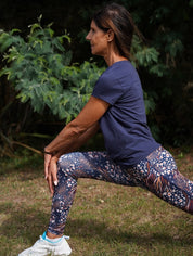 Nachhaltige Sportmode – Frau macht Yoga im marineblauen „Toucan“-T-Shirt, weich & dehnbar für maximale Flexibilität