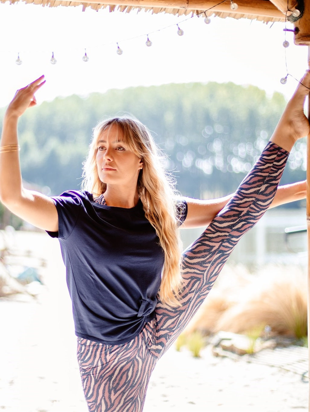 Dynamische Yoga-Pose im Freien – Frau trägt das nachhaltige „Toucan“-T-Shirt in Marineblau mit ergonomischem Schnitt