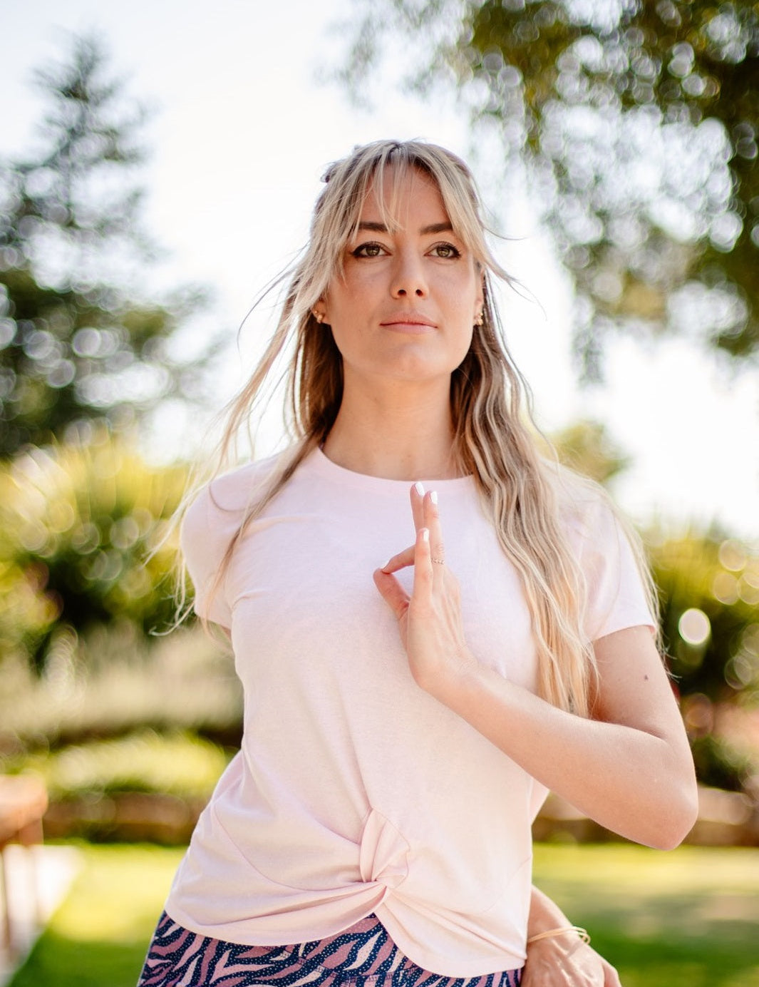 Frau praktiziert Yoga im Freien mit dem nachhaltigen Yoga- & Fitness-T-Shirt – Rosa „Toucan