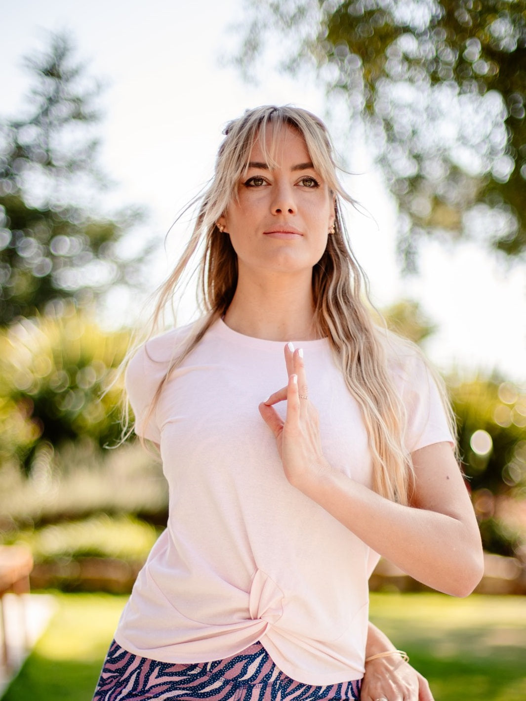 Frau praktiziert Yoga im Freien mit dem nachhaltigen Yoga- & Fitness-T-Shirt – Rosa „Toucan