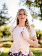 Frau praktiziert Yoga im Freien mit dem nachhaltigen Yoga- & Fitness-T-Shirt – Rosa „Toucan