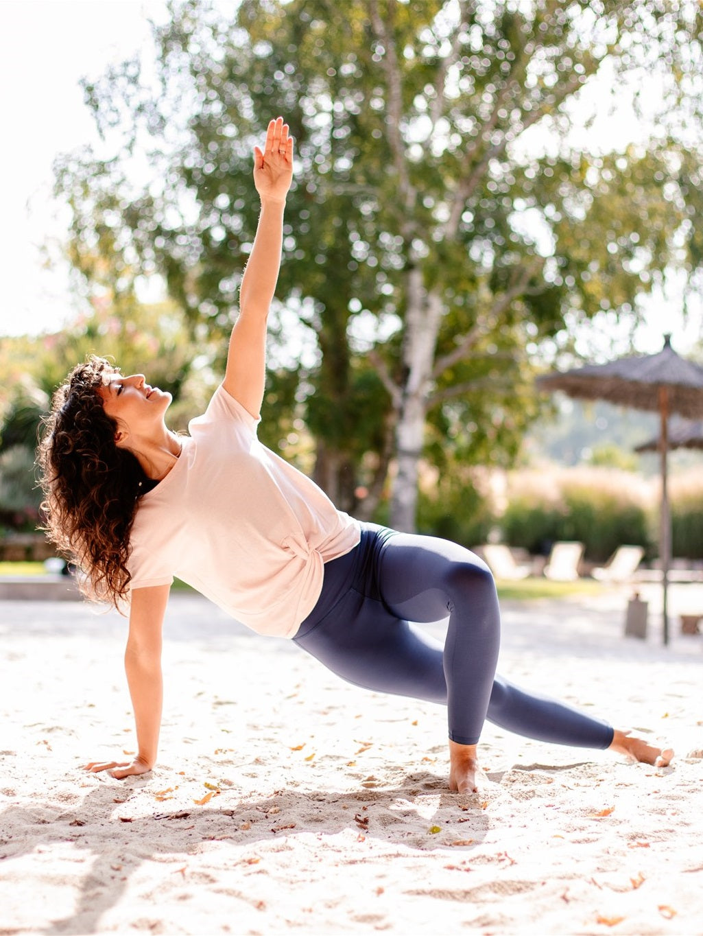 Frau macht Dehnübungen im Freien mit dem bequemen Yoga- & Fitness-T-Shirt – Rosa „Toucan