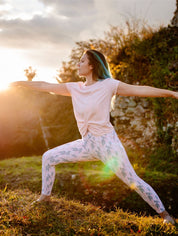 Frau hält eine Yoga-Pose im Freien mit dem nachhaltigen Yoga- & Fitness-T-Shirt – Rosa „Toucan