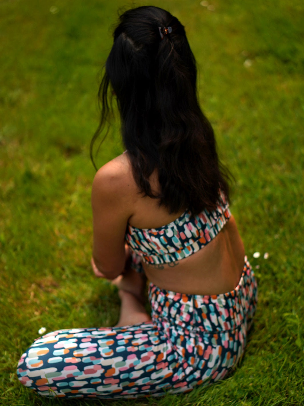Frau beim Yoga draußen, Rückansicht: MÉSANGE-Sport-Bustier mit grafischem Buntmotiv und passendem Legging, nachhaltig hergestellt in Frankreich.