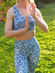 Frau steht draußen in entspannter Pose, trägt das Sport-Bustier Mésange Margeriten-Motiv und passendes Leggings.