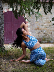 Frau trägt das Sport-Bustier Mésange mit Margeriten-Motiv und passendem Leggings beim Yoga im Freien, frontal aufgenommen.