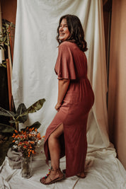 Modell in Studioaufnahme trägt das lange Stillkleid Tania mit Empire-Schnitt und Schmetterlingsärmeln – feminine Eleganz in voller Länge.