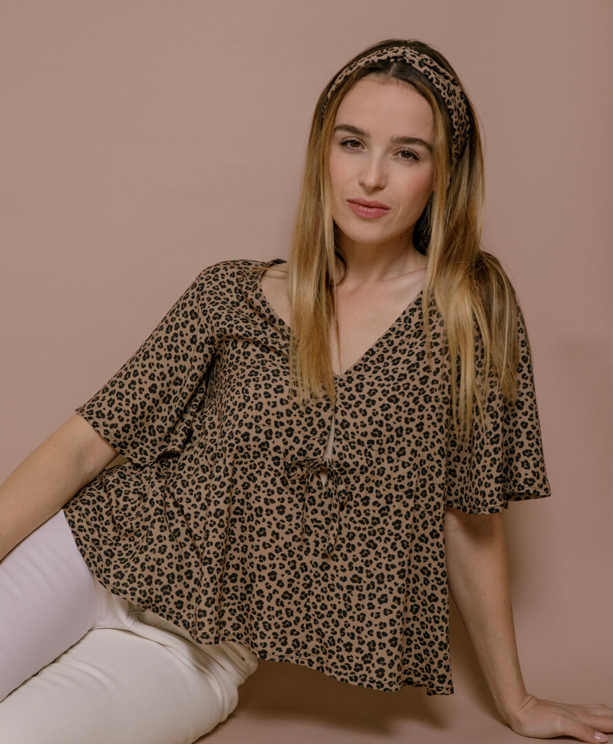 Frau sitzt mit Leo-Blusentop aus nachhaltiger EcoVero-Viskose, moderner Sommer-Look, elegante Damenmode made in France.