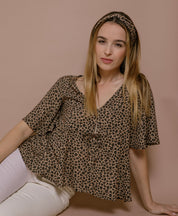 Frau sitzt mit Leo-Blusentop aus nachhaltiger EcoVero-Viskose, moderner Sommer-Look, elegante Damenmode made in France.