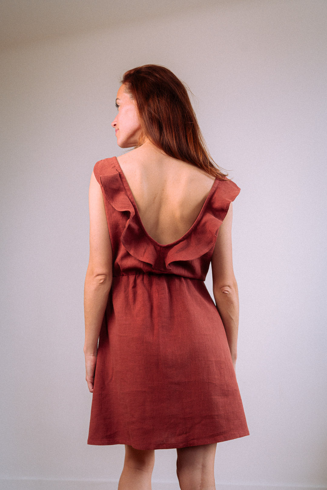 Rückenansicht des Kleids "Mathilde" im Studio – umweltfreundliches Sommerkleid aus 100 % Leinen mit V-Ausschnitt und zartem Volant am Rücken.