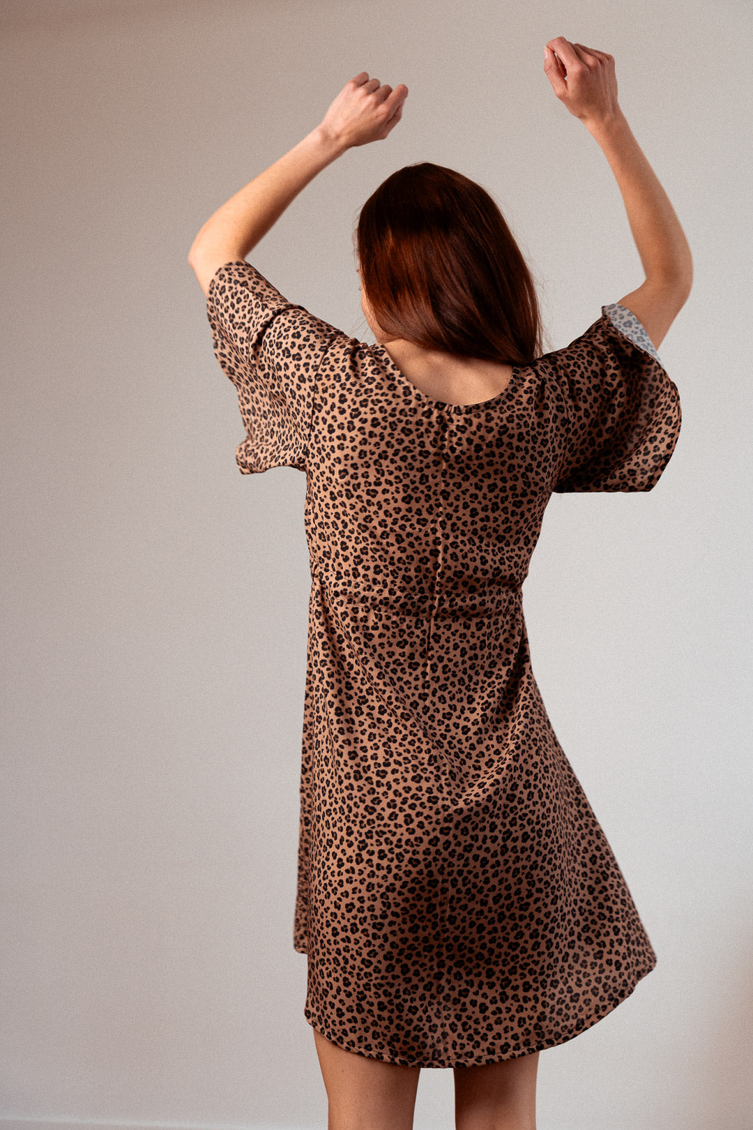  Frau trägt das Sommerkleid von hinten, Blick auf den Rücken – nachhaltig produziert in Frankreich, mit fließendem EcoVero™-Viskose-Stoff und raffinierten Details.
