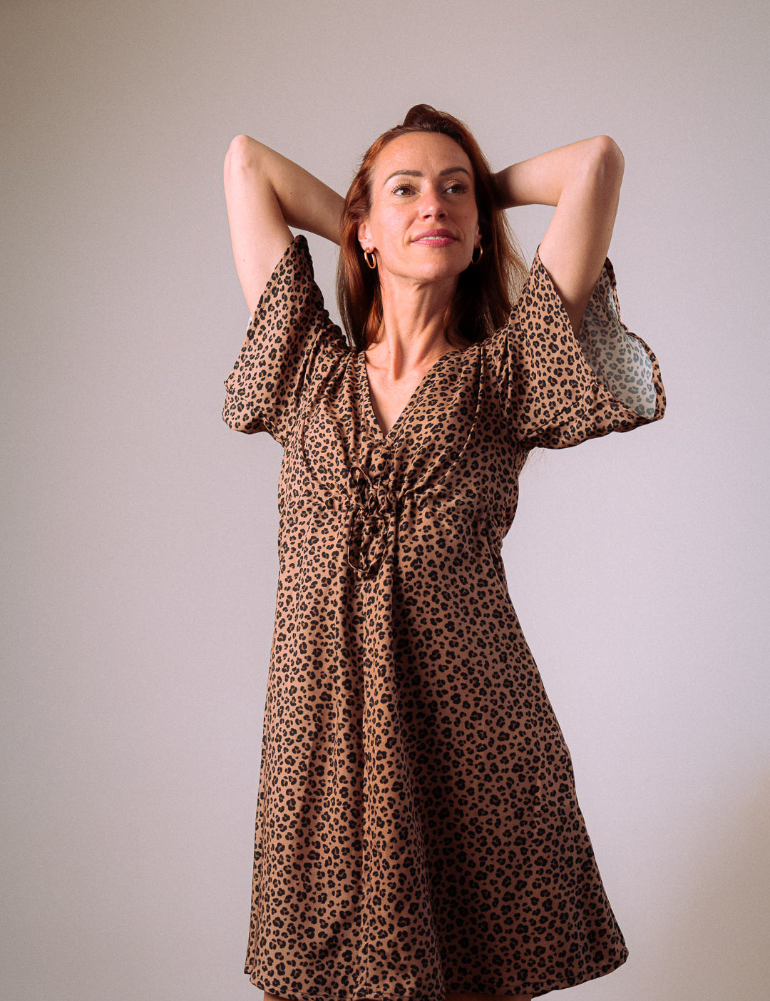 Frau im Studio trägt Sommerkleid mit Leo-Print – elegante Silhouette, umweltfreundlicher Stoff aus EcoVero™-Viskose und femininer Schnitt für stilvolle Damenmode.