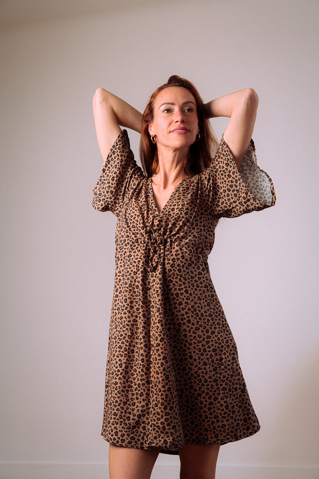 Frau im Studio trägt Sommerkleid mit Leo-Print – elegante Silhouette, umweltfreundlicher Stoff aus EcoVero™-Viskose und femininer Schnitt für stilvolle Damenmode.