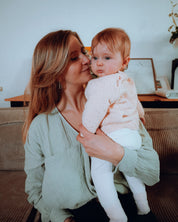 Stillbluse Tiphaine in Aqua-Grün – Mutter hält ihr Baby im Arm, trägt eine bequeme Stillbluse aus Bio-Baumwolle.