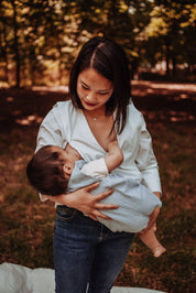 Frau stillt ihr Baby draußen in der Stillbluse Camille – diskret, stilvoll und perfekt für den Alltag.