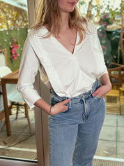 Frau trägt die weiße Stillbluse Camille in einem hellen Innenraum – zeitloses Design trifft auf funktionale Eleganz.