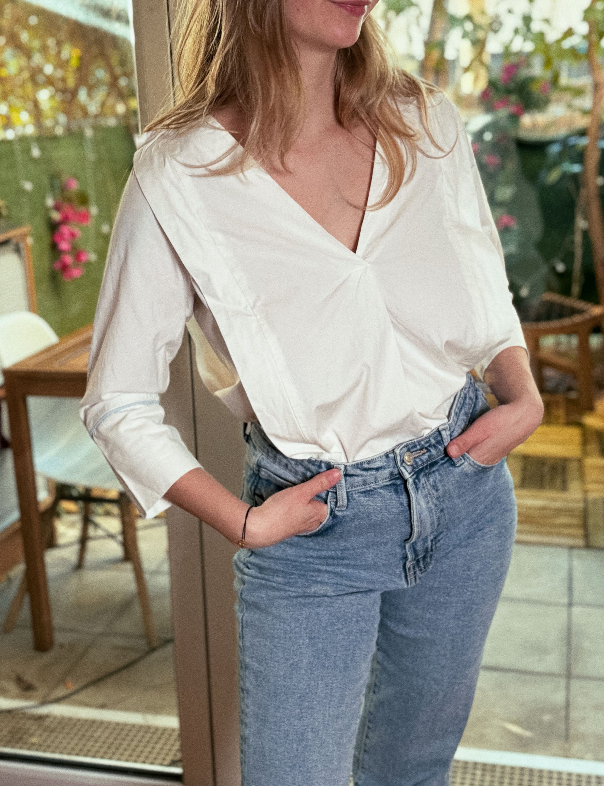 Frau trägt die weiße Stillbluse Camille in einem hellen Innenraum – zeitloses Design trifft auf funktionale Eleganz.