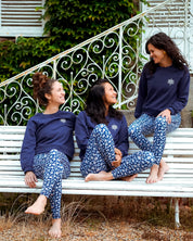 Drei Frauen tragen das Sweatshirt 'Héron' in Marineblau beim Yoga im Freien – elegantes, vielseitiges Design für Sport und Entspannung.
