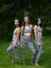 Drei Frauen tragen den COLIBRI-Leggings mit grafischem Buntmotiv und passender Sport-Bustier, stehend in der Natur.