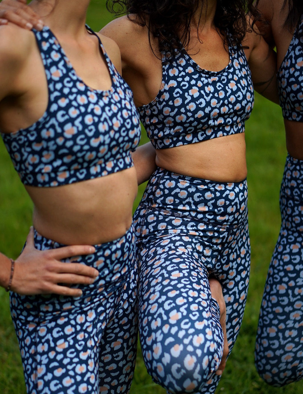 Nahaufnahme des Sport-Bustier Mésange und Colibri-Leggings im Leo-Print blau an drei Frauen, zeigt Passform, Details und nachhaltige Materialien