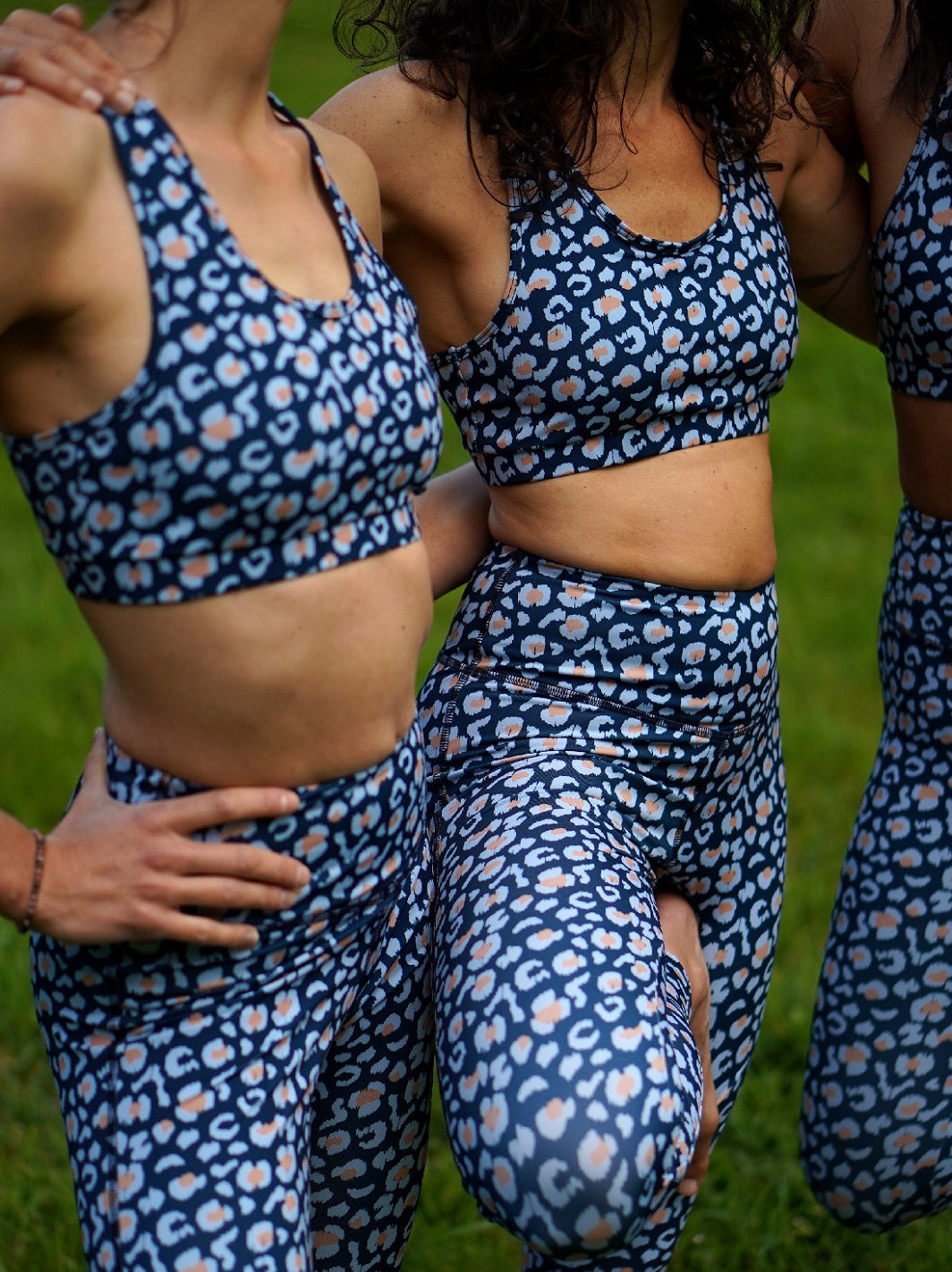 Nahaufnahme des Sport-Bustier Mésange und Colibri-Leggings im Leo-Print blau an drei Frauen, zeigt Passform, Details und nachhaltige Materialien