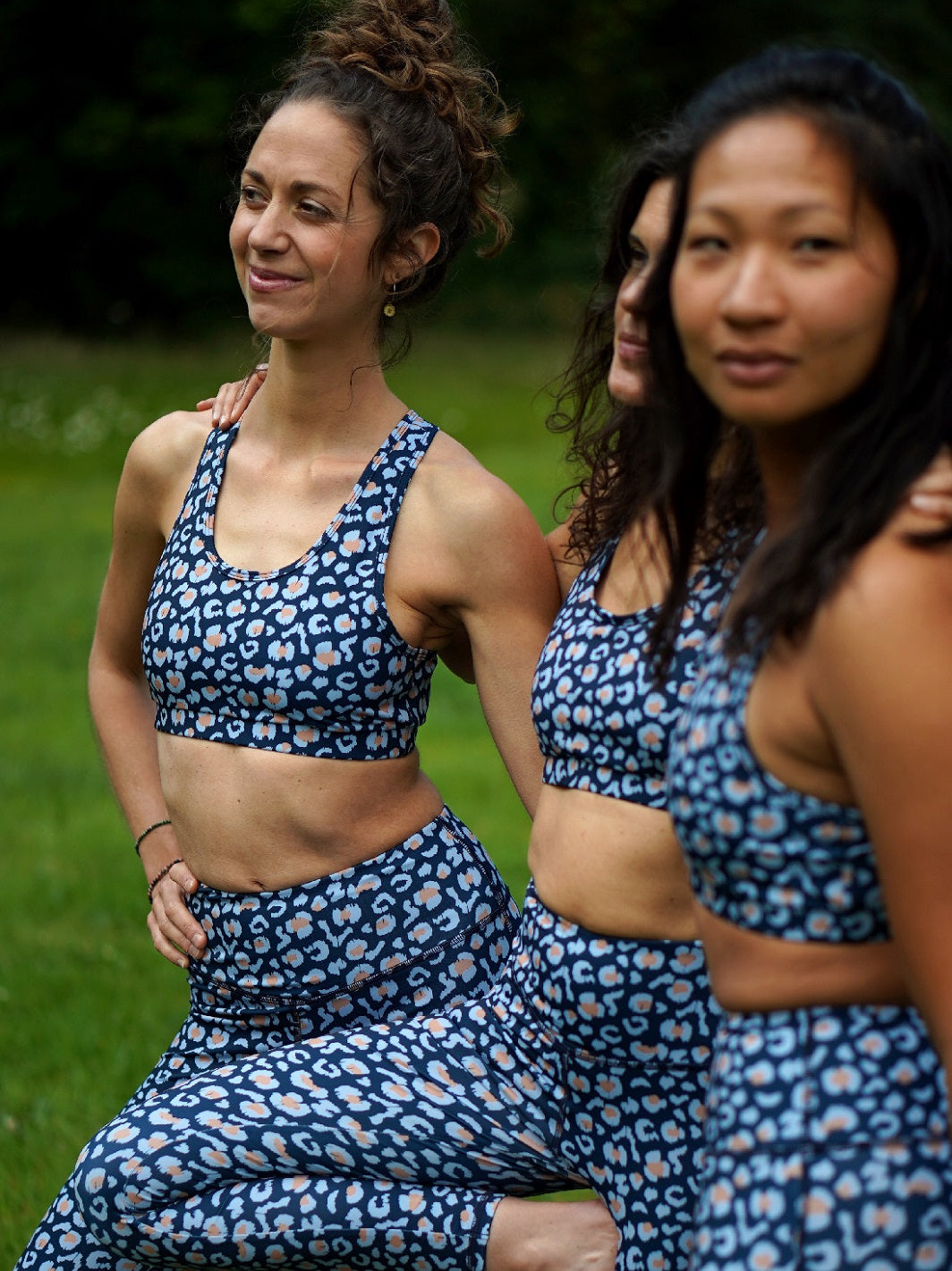 Drei Frauen tragen Sport-Bustier Mésange und Colibri-Leggings im Leo-Print blau beim Training, Yoga und Fitnessübungen, nachhaltige Sportbekleidung aus recyceltem Polyester