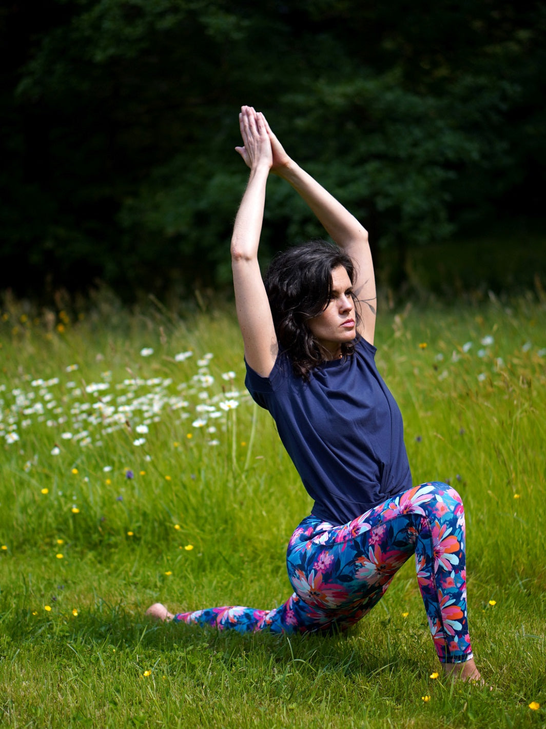 Frau in französischem Sport-Outfit mit Lotusblüten-Muster beim Yoga im Park.